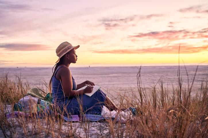 young woman sitting on the beach at sunset